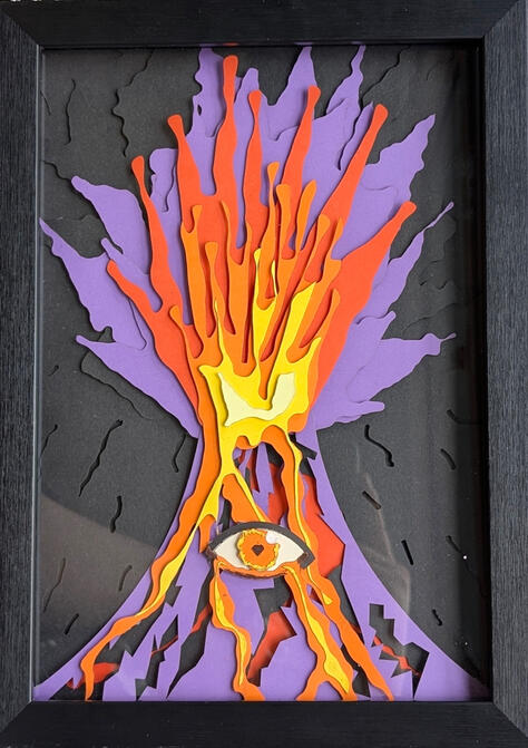 A photo of a framed artwork of a volcano with an eye crying lava formed with layers of laser cut paper.